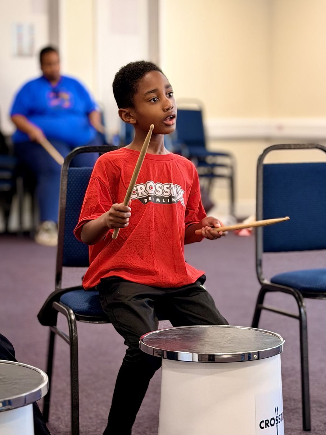 A young drummer with sticks raised high above his head