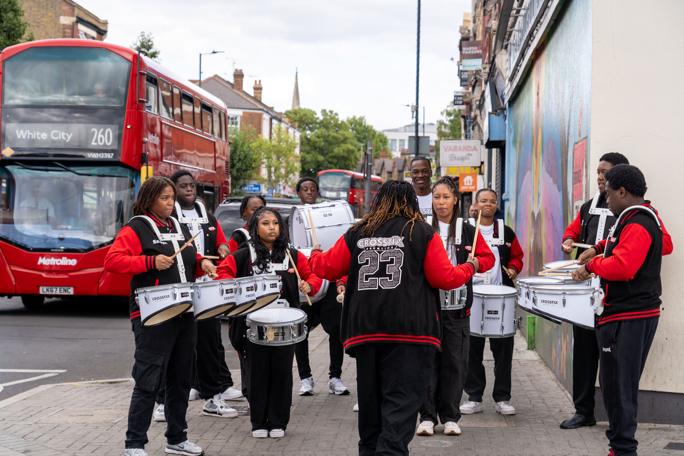 CrosStix marching beside a red double-decker bus