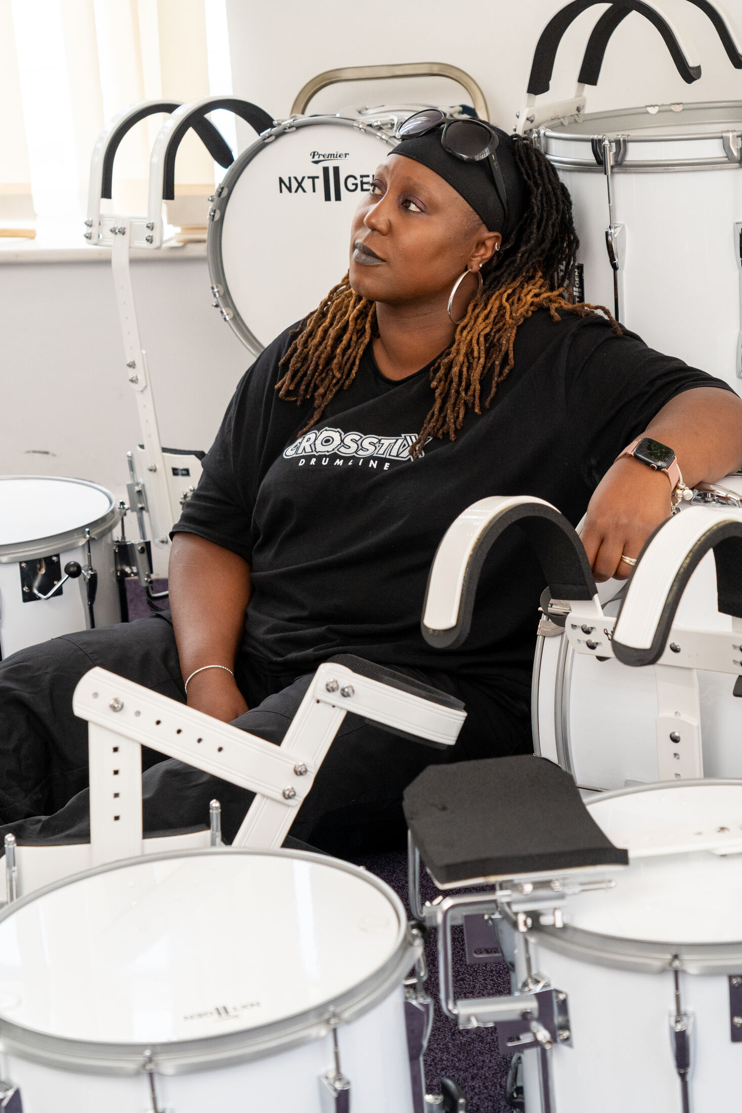 Nadine Lee, founder of CrosStix, seated among white marching drums