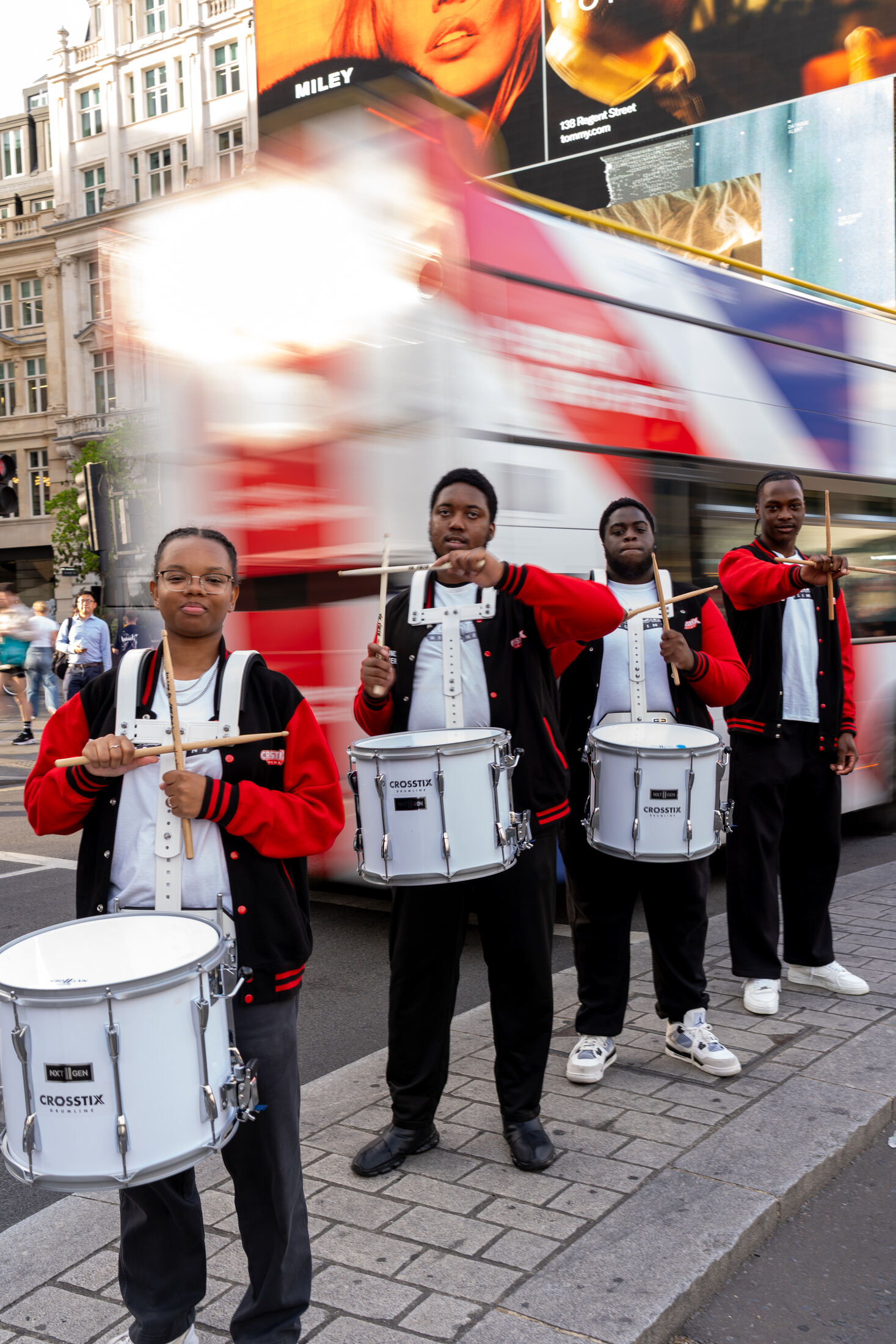CrosStix drummers with a London bus streaking behind